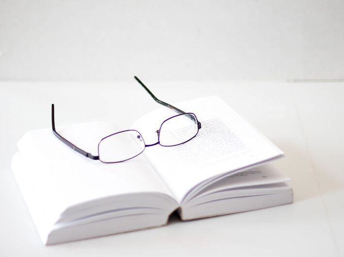 An pair of glasses sits on an open book.